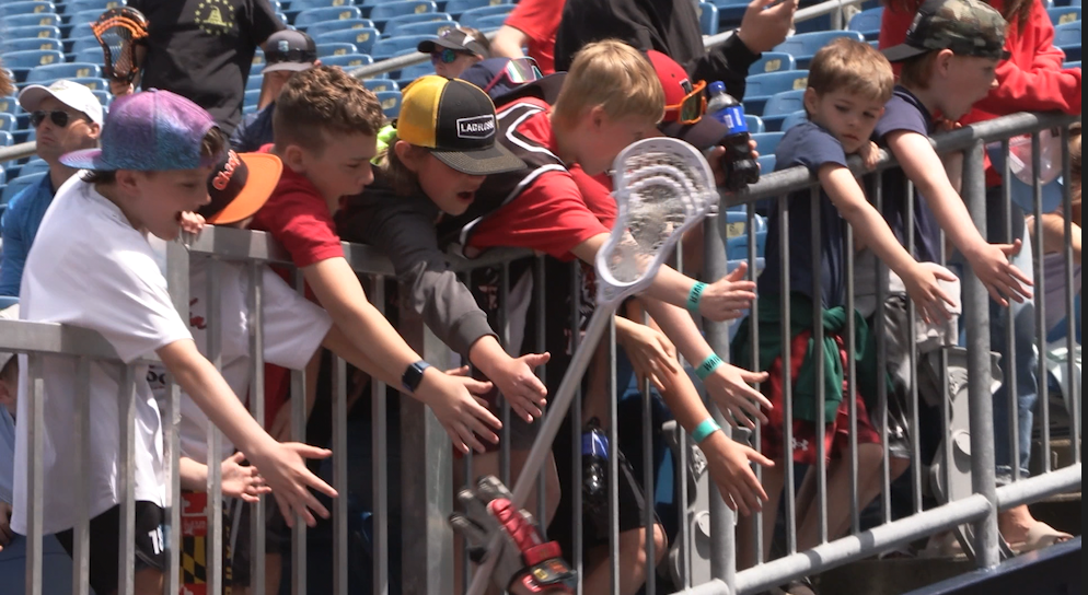 Youth lacrosse fans line the fence as Maryland walks out for the championship game.